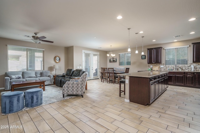 kitchen featuring a kitchen breakfast bar, a center island, tasteful backsplash, light stone counters, and decorative light fixtures