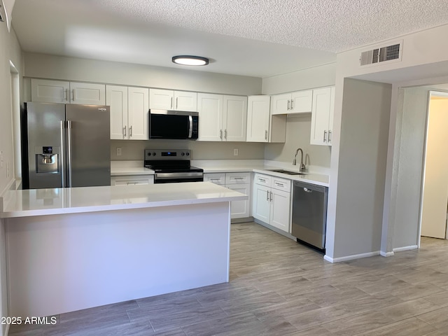 2155 W Farmdale Ave Unit 8, Mesa, AZ 85202 - kitchen with stainless steel appliances, a sink, light countertops, white cabinetry, and a textured ceiling