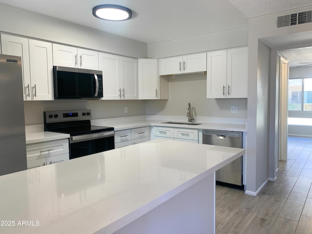 2155 W Farmdale Ave Unit 8, Mesa, AZ 85202 - kitchen featuring appliances with stainless steel finishes, a sink, light wood finished floors, white cabinetry, and baseboards