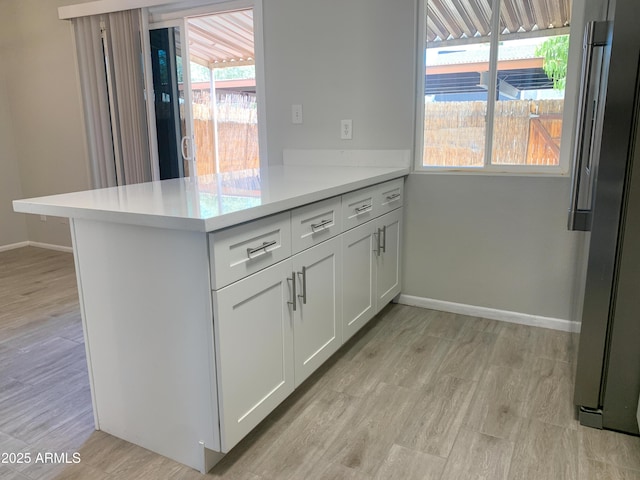 2155 W Farmdale Ave Unit 8, Mesa, AZ 85202 - kitchen featuring light countertops, a peninsula, baseboards, white cabinetry, and healthy amount of natural light