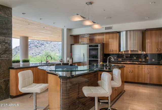 kitchen with appliances with stainless steel finishes, brown cabinetry, visible vents, and a sink