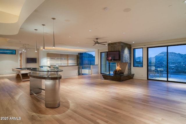 interior space featuring light wood-style floors, a fireplace, a kitchen island, and open floor plan