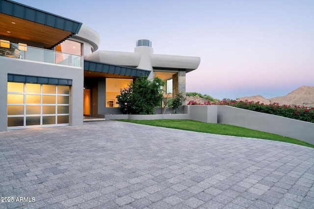 view of front of property with a garage, decorative driveway, a standing seam roof, and stucco siding