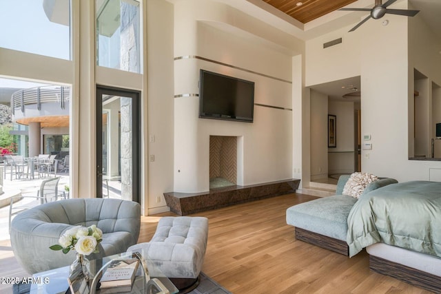 living room with a towering ceiling, light wood-style flooring, visible vents, and a wealth of natural light