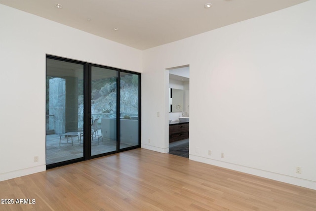 spare room with baseboards and wood finished floors