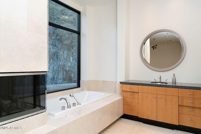 bathroom with a garden tub, tile patterned flooring, and vanity