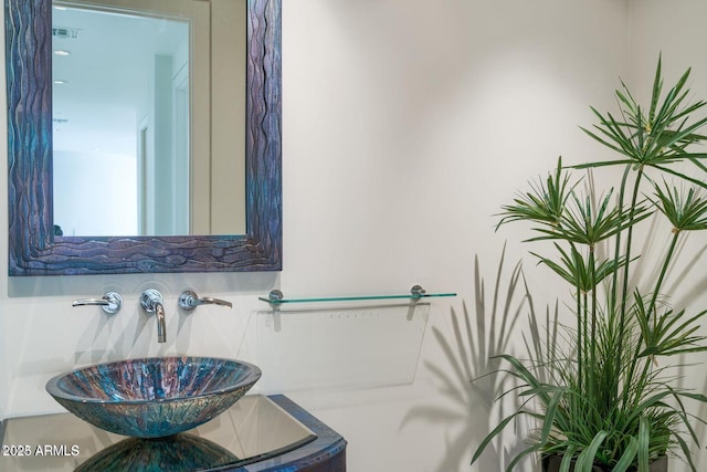 bathroom featuring tasteful backsplash, visible vents, and a sink