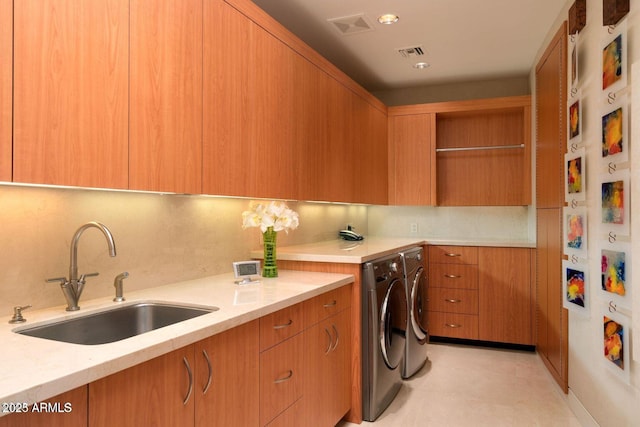 laundry room with visible vents, washer and clothes dryer, a sink, and cabinet space