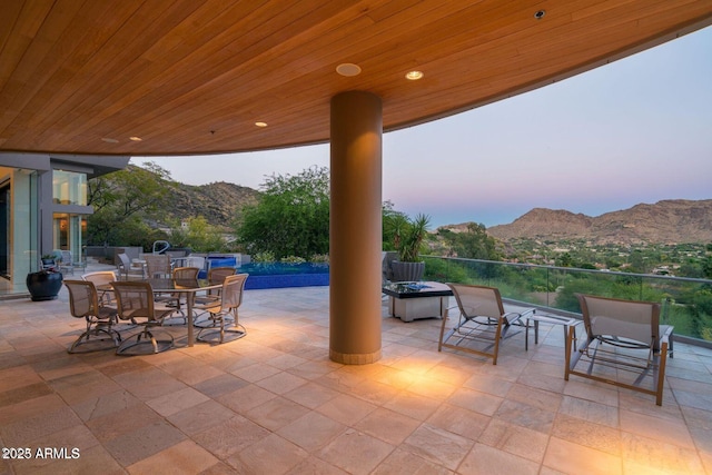 patio terrace at dusk featuring outdoor dining area and a mountain view