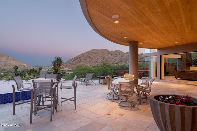 patio terrace at dusk featuring outdoor dining area and a mountain view