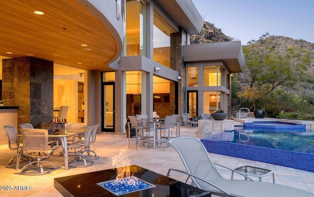 exterior space with a patio area, an infinity pool, a fire pit, and outdoor dining space