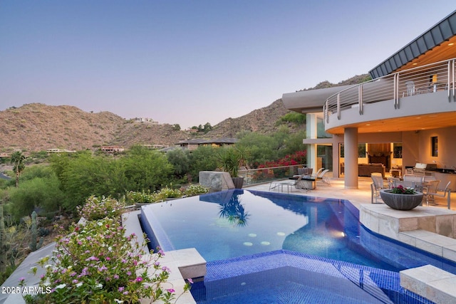 view of pool featuring a patio, outdoor dining space, a pool with connected hot tub, and a mountain view