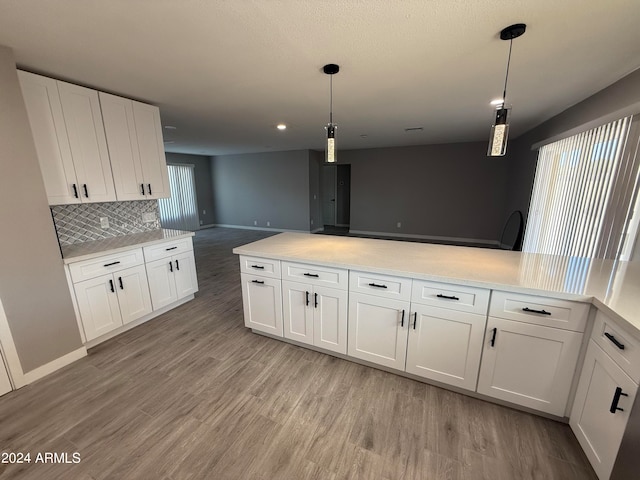 kitchen featuring pendant lighting, tasteful backsplash, light wood-type flooring, and white cabinetry