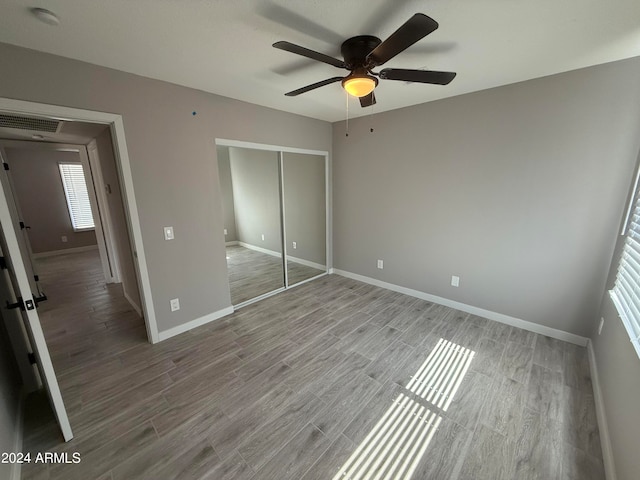 unfurnished bedroom featuring ceiling fan, a closet, and wood-type flooring