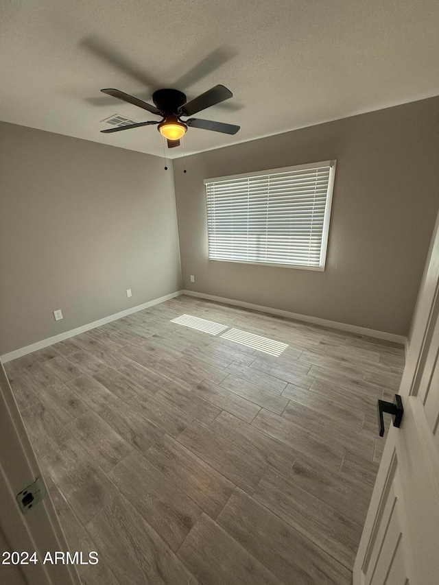 unfurnished room featuring ceiling fan, a textured ceiling, and light hardwood / wood-style flooring