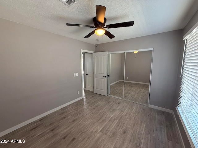 unfurnished bedroom featuring ceiling fan, a textured ceiling, a closet, and dark wood-type flooring