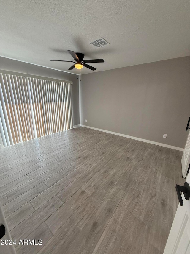 unfurnished room featuring a textured ceiling, light wood-type flooring, and ceiling fan