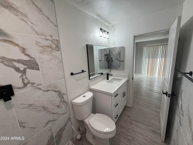 bathroom with vanity, toilet, a textured ceiling, and hardwood / wood-style flooring