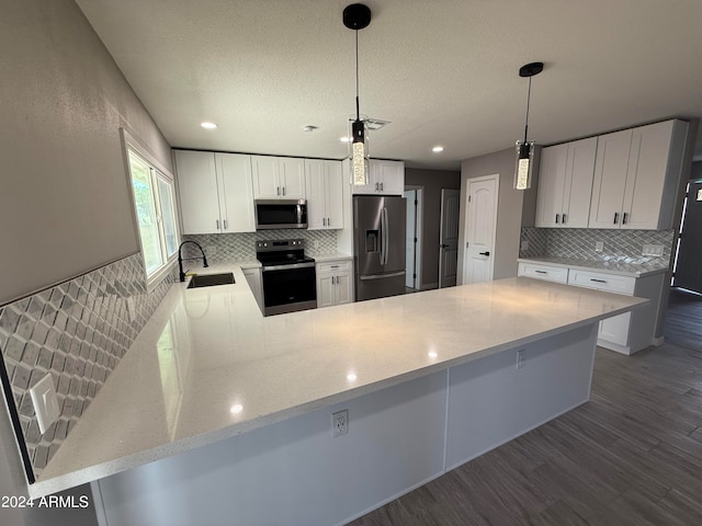 kitchen featuring dark hardwood / wood-style floors, white cabinets, sink, kitchen peninsula, and appliances with stainless steel finishes