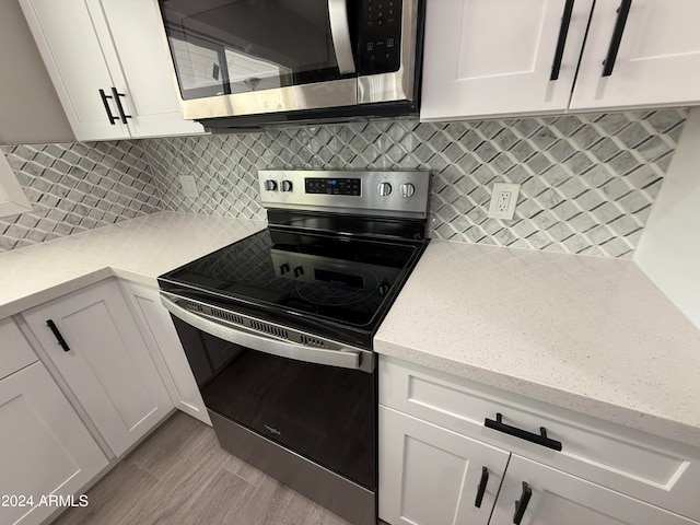 kitchen featuring light stone counters, white cabinets, light hardwood / wood-style floors, appliances with stainless steel finishes, and backsplash