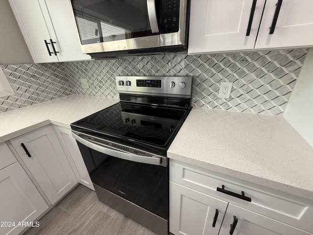 2429 E Alameda Dr, Tempe, AZ 85282 - kitchen with backsplash, light wood-style floors, white cabinetry, light stone countertops, and appliances with stainless steel finishes