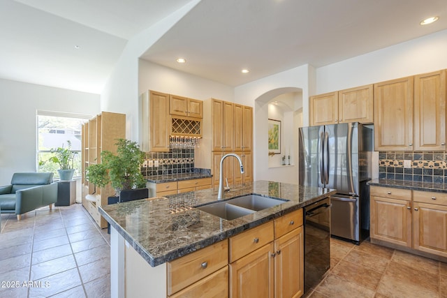 kitchen with freestanding refrigerator, black dishwasher, a sink, decorative backsplash, and arched walkways