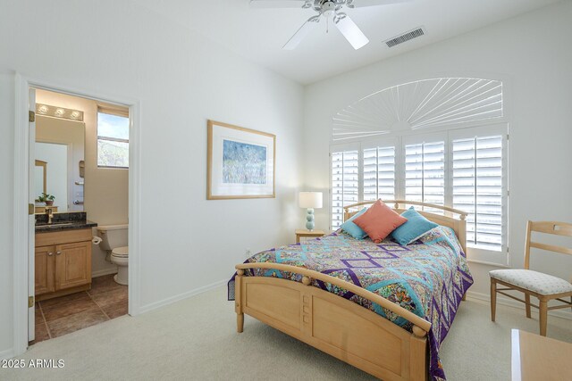 bedroom with a sink, ensuite bathroom, visible vents, light carpet, and baseboards