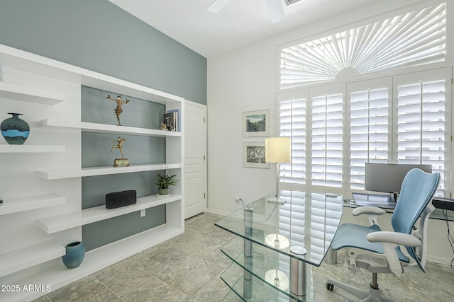 office space with a ceiling fan, baseboards, and stone finish flooring