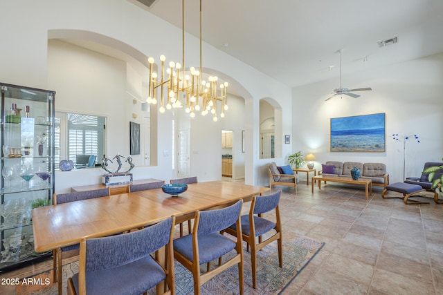 dining area featuring arched walkways, visible vents, a high ceiling, and ceiling fan with notable chandelier