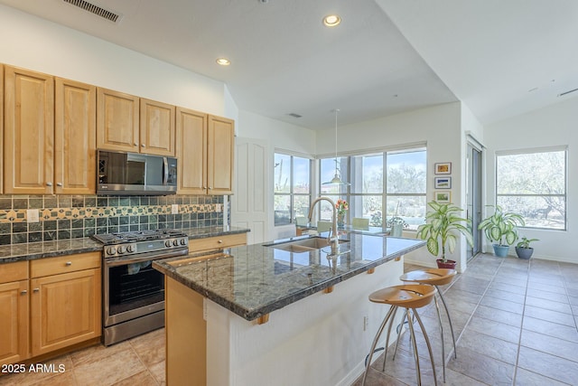 kitchen featuring a kitchen bar, a sink, visible vents, appliances with stainless steel finishes, and decorative backsplash