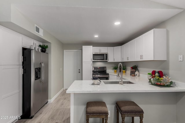 8720 W Willowbrook Dr, Peoria, AZ 85382 - kitchen featuring stainless steel appliances, a peninsula, light wood-style floors, white cabinetry, and recessed lighting