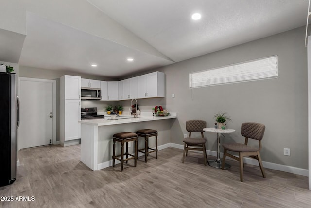 8720 W Willowbrook Dr, Peoria, AZ 85382 - kitchen with stainless steel appliances, lofted ceiling, a peninsula, a breakfast bar area, and recessed lighting