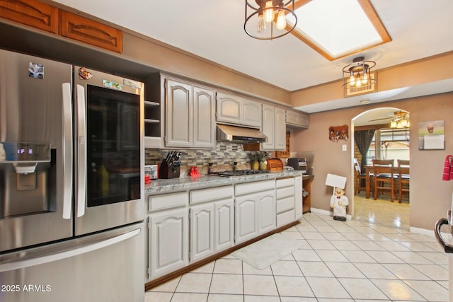 kitchen with under cabinet range hood, appliances with stainless steel finishes, light tile patterned flooring, light countertops, and decorative backsplash