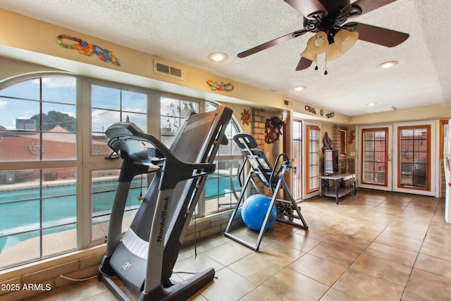 workout area with visible vents, a textured ceiling, and ceiling fan