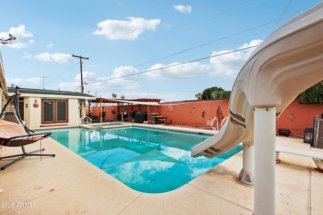 view of swimming pool with fence, a patio area, a fenced in pool, and a water slide