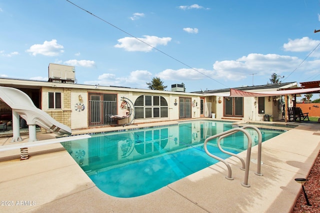 outdoor pool featuring a patio, a diving board, and a water slide