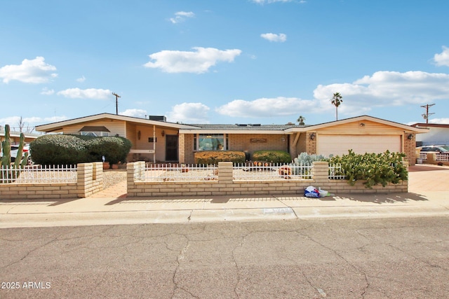 view of front of house with a fenced front yard, driveway, brick siding, and a garage