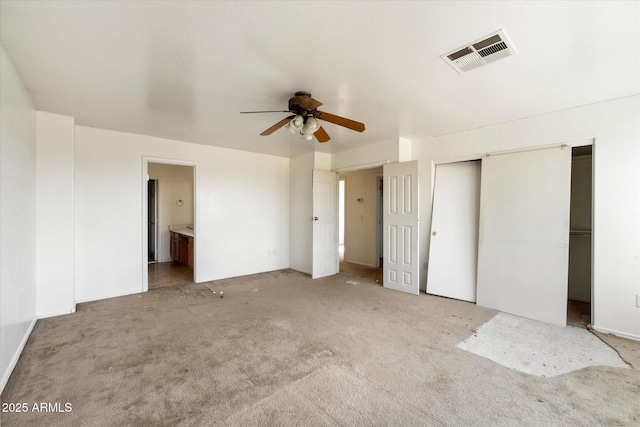 unfurnished bedroom with ensuite bathroom, light colored carpet, ceiling fan, and a closet