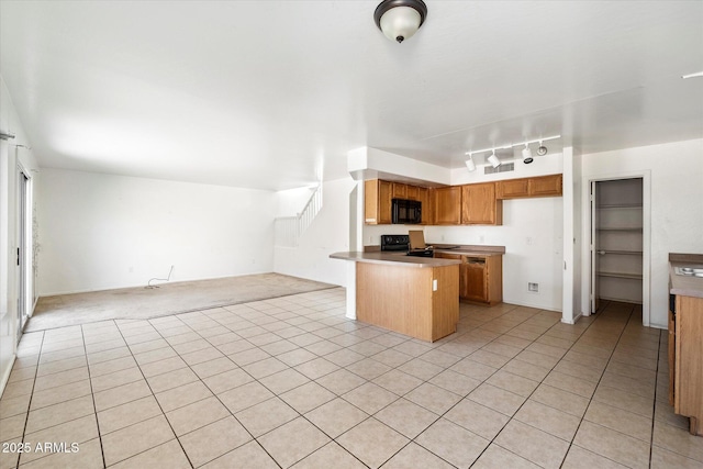 kitchen featuring rail lighting, kitchen peninsula, light tile patterned floors, and black appliances