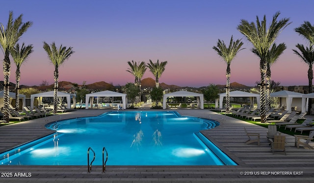 pool at dusk featuring a gazebo