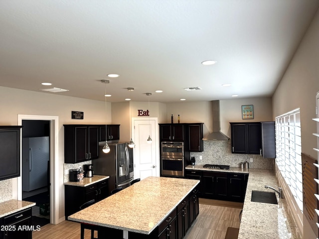 kitchen featuring wall chimney exhaust hood, sink, tasteful backsplash, a center island, and stainless steel appliances