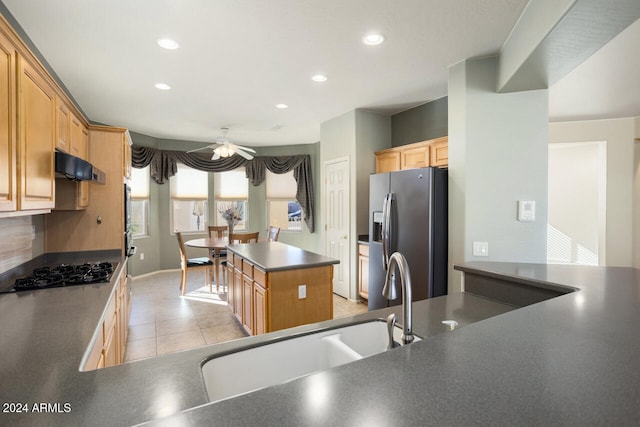 kitchen featuring ventilation hood, black gas stovetop, sink, stainless steel refrigerator with ice dispenser, and a kitchen island