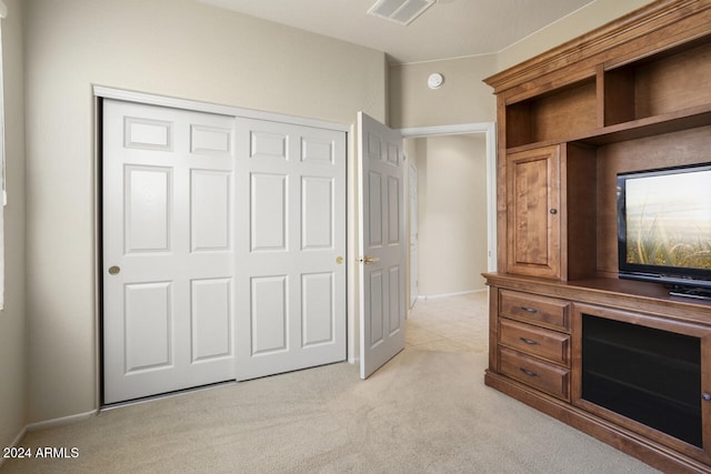 unfurnished bedroom featuring light carpet and a closet