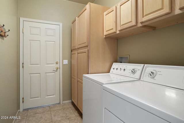 clothes washing area featuring light tile patterned floors, cabinets, and independent washer and dryer