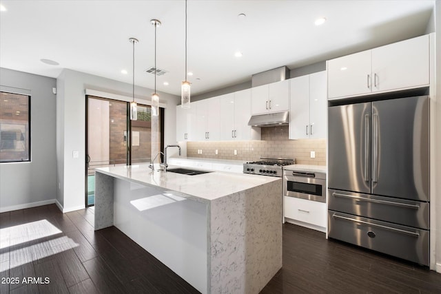 kitchen with hanging light fixtures, white cabinetry, sink, and stainless steel refrigerator