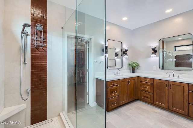 bathroom featuring double vanity, tiled shower, and a sink