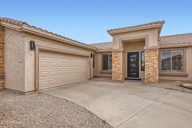 view of front facade with stucco siding, concrete driveway, an attached garage, and a tiled roof