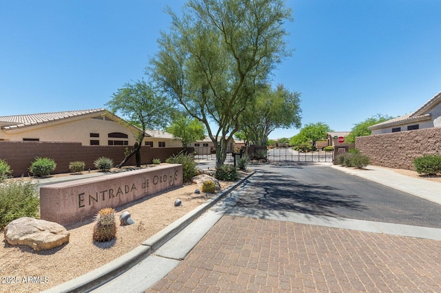 view of street featuring curbs, a gated entry, traffic signs, and a gate