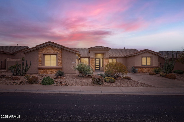 view of front of home with stone siding, stucco siding, driveway, and a tile roof