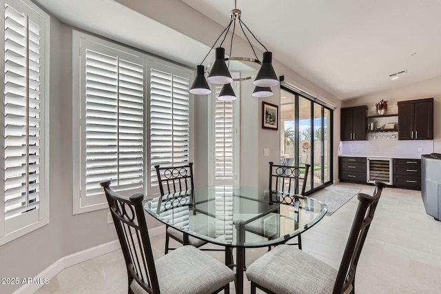 dining area featuring beverage cooler, visible vents, baseboards, and lofted ceiling